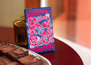 Blue and red box of Birdsnake chocolate bar resting against a gold jar.