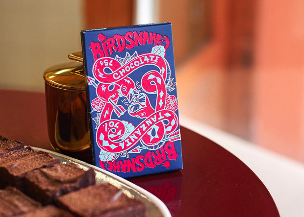 Blue and red box of Birdsnake chocolate bar resting against a gold jar.
