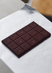 Dark brown block of Birdsnake chocolate laying upon a sheet of white paper.