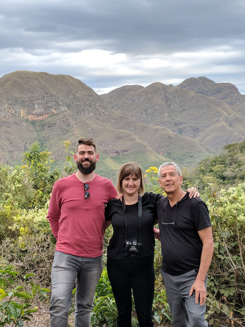 Three coffee enthusiasts standing in front of a large mountain in Bolivia.